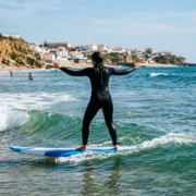 A beginner riding their first small green wave on a soft board near Lisbon