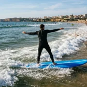 A beginner riding white-water on a soft surfboard at a sandy beach near Lisbon